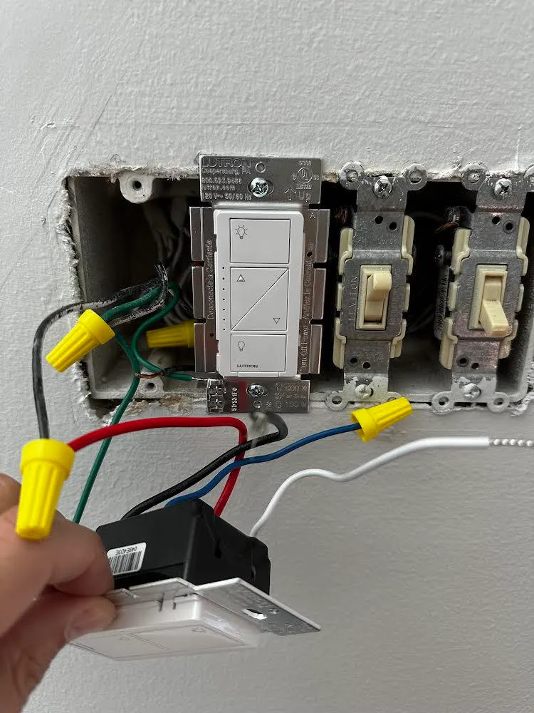 An opened wall switch box reveals exposed wiring and a partially installed Lutron Smart Switch next