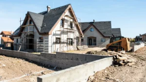 A house under construction with scaffolding, a partially built concrete wall, electrical services