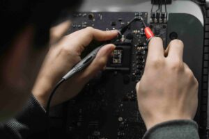 Close-up of hands using test probes to examine components on a circuit board—a perfect example when